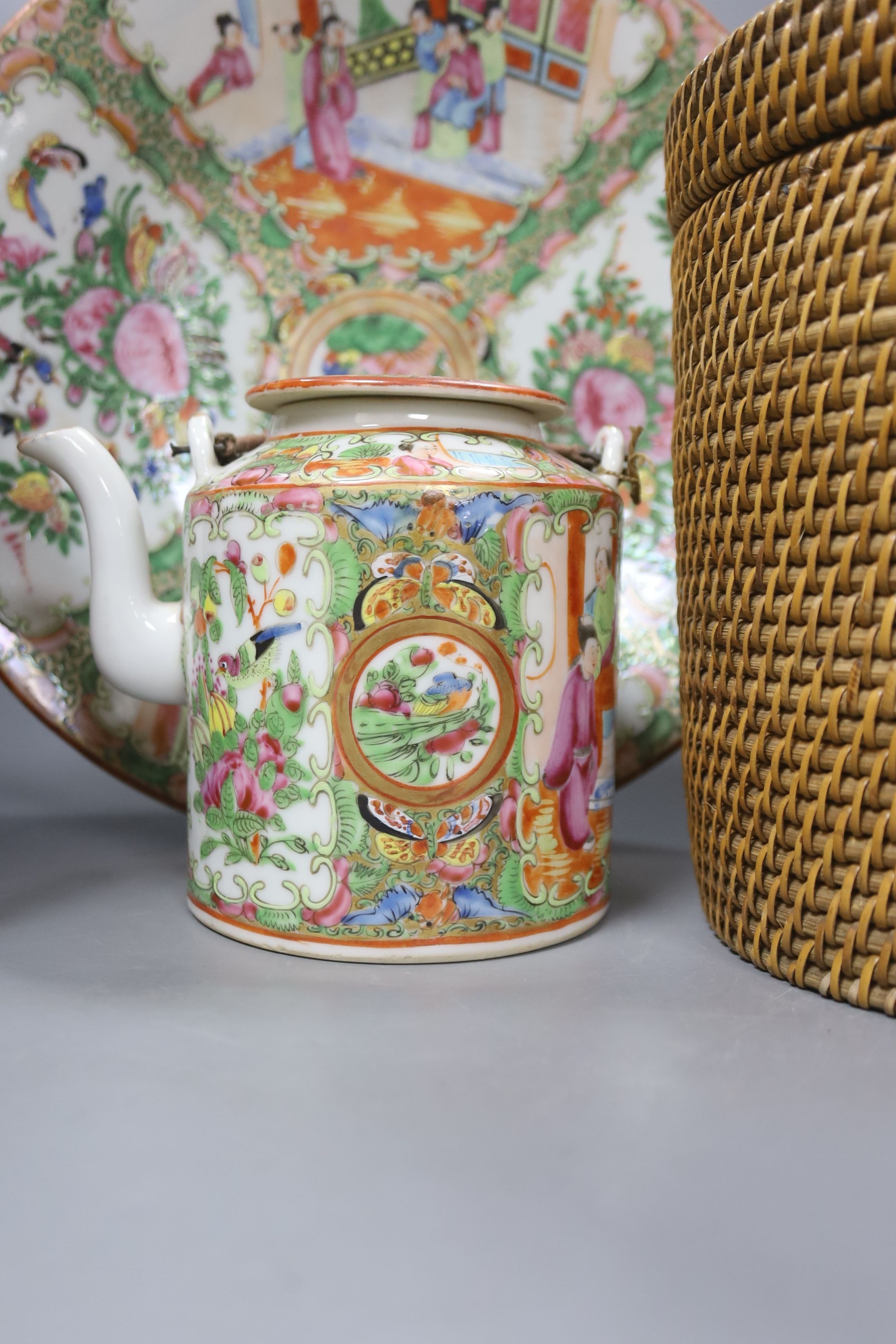 Three late 19th/early 20th century Chinese famille teapots, two in baskets and a similar dish, dish 29.5 cms diameter.